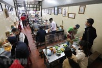 Quán ăn trong nhà lắp tấm chắn giữa các vị trí ngồi đảm bảo phòng chống dịch. (Ảnh: Thành Đạt/TTXVN).
