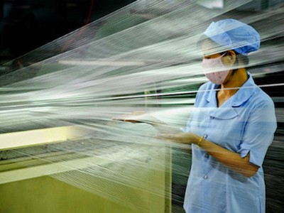 Công nhân kiểm tra chất lượng sợi trên dây chuyền sản xuất.