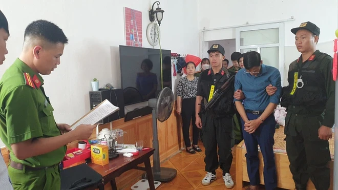 Phạm Trung Kiên (áo xanh than) nghe đọc lệnh khám xét khẩn cấp tại nhà riêng (Ảnh: PX03 Điện Biên).