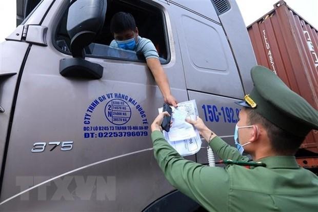 Lực lượng chức năng tại chốt kiểm dịch đầu cầu Trung Hà, huyện Ba Vì kiểm tra giấy thông hành và thẻ “luồng xanh” của các phương tiện vận tải ra, vào thành phố tháng 8/2021. (Ảnh: Tuấn Anh/TTXVN)