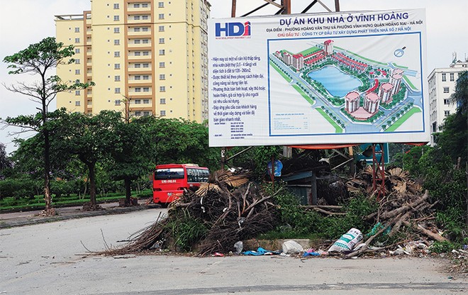 Bảng thông tin hướng dẫn chi tiết về dự án Khu nhà ở Vĩnh Hoàng, phía dưới là một bãi rác