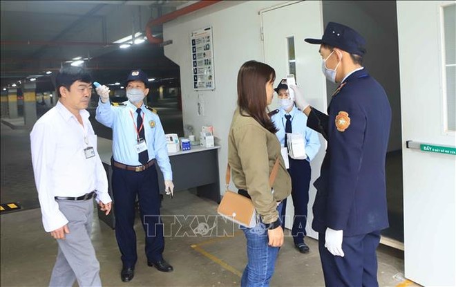 Trong ảnh: Đo nhiệt độ cho công nhân trước khi vào làm việc tại Công ty TNHH sản xuất hàng may mặc Việt Nam (TAL), khu công nghiệp Bá Thiện 2 (huyện Bình Xuyên). Ảnh: Hoàng Hùng - TTXVN