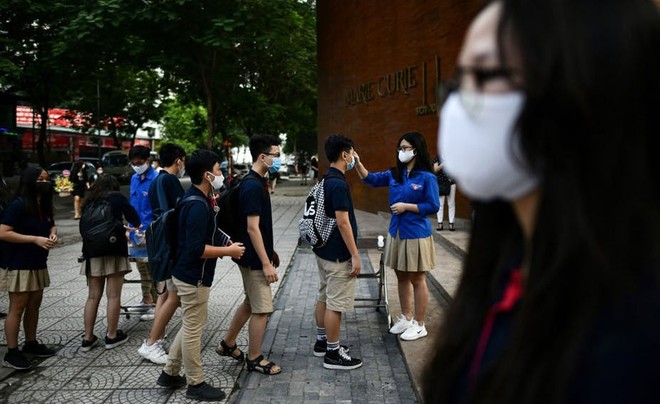 Kiểm tra thân nhiệt đối với học sinh tại các trường học ở Hà Nội. Ảnh: AFP