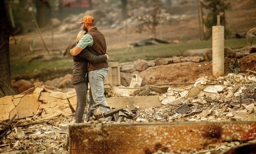 Cặp vợ chồng ôm nhau giữa ngôi nhà đã bị ngọn lửa thiêu hủy hoàn toàn tại thị trấn Paradise hôm 12/11. Ảnh: AP.