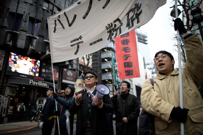 "Liên minh Cách mạng Những người đàn ông Kém sức hút" cầm băng rôn và biểu ngữ phản đối Lễ Tình nhân đi dọc con phố Shibuya, Tokyo, Nhật Bản. Ảnh: Reuters. 