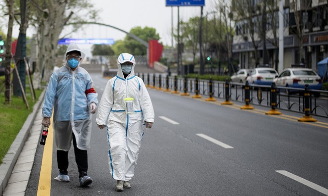 Dân Vũ Hán mặc đồ bảo hộ đi trên phố ngày 31/3. Ảnh: AFP.