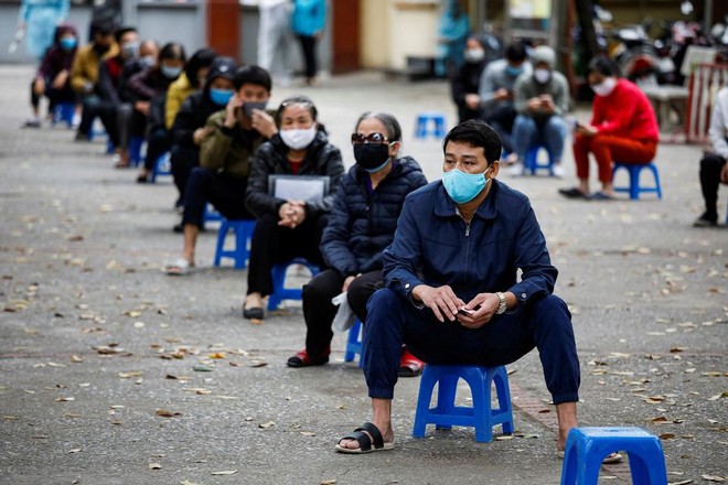 Người dân ngồi cách xa nhau trong khi chờ đến lượt tại một cơ sở xét nghiệm nhanh ở Hà Nội. Ảnh: Reuters.