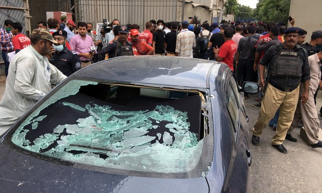 Đám đông tụ tập gần một chiếc xe bị bắn vỡ cửa kính tại lối vào sở giao dịch chứng khoán ở Karachi, Pakistan hôm nay. Ảnh: Reuters.