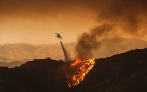 Máy bay trực thăng thả nước dập tắt các đám cháy tại Santa Clarita. Ảnh AFP.