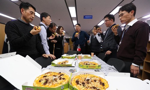Cán bộ Bộ Chiến lược và Tài chính Hàn Quốc thưởng thức pizza do Tổng thống Moon Jae-in tặng. Ảnh: Yonhap