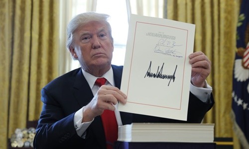 Tổng thống Mỹ Donald Trump cầm bản cải cách thuế với chữ ký của ông tại Phòng Bầu dục, Nhà Trắng, ngày 22/12 (Ảnh: VnEpress/Reuters)