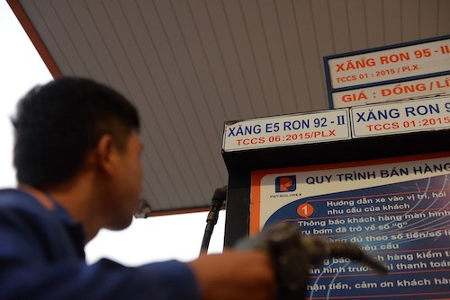 Nhân viên cây xăng tại TP HCM xem bảng giá trước khi bơm xăng cho khách. Ảnh: Hữu Khoa.