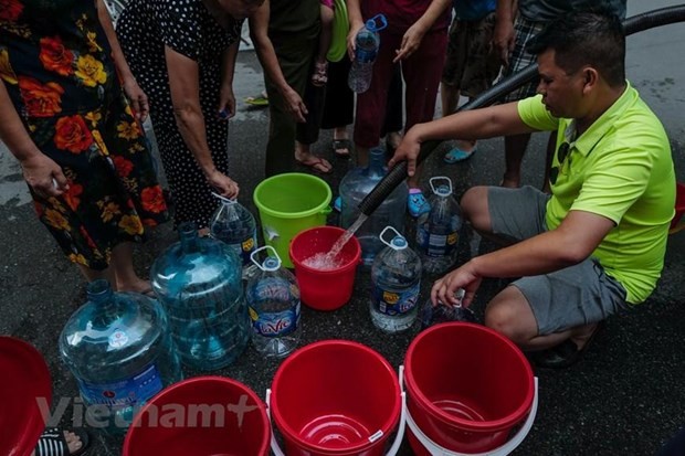 Người dân xếp hàng lấy nước sạch. (Ảnh: PV/Vietnam+).