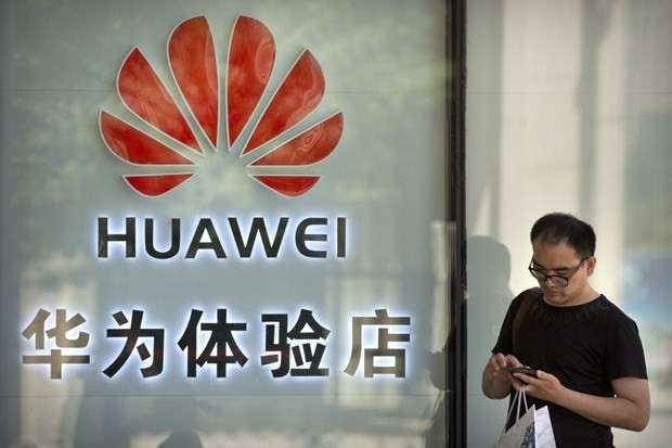 Một người đang sử dụng điện thoại bên ngoài cửa hàng Huawei ở Bắc Kinh. (Nguồn: AP)