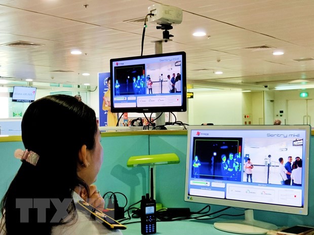 Nhân viên sân bay Tân Sơn Nhất theo dõi trên màn hình hiển thị máy quét thân nhiệt đối với hành khách quốc tế đến Việt Nam. (Ảnh: Đinh Hằng/TTXVN).