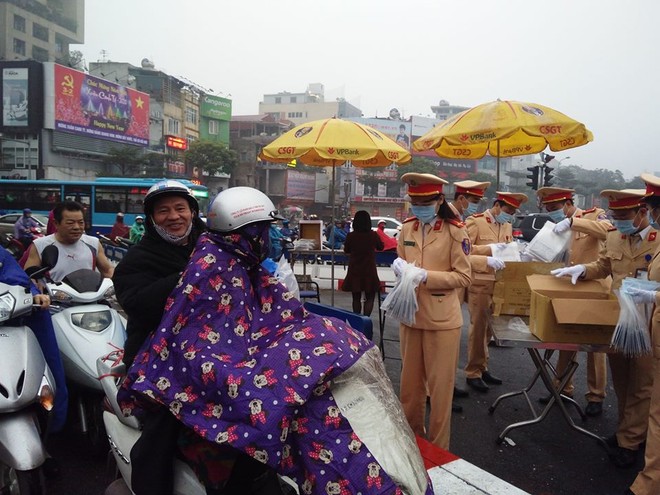 Hình ảnh lực lượng CSGT Hà Nội phát khẩu trang miễn phí cho người tham gia giao thông tại nút giao Xã Đàn - Ô Chợ Dừa.