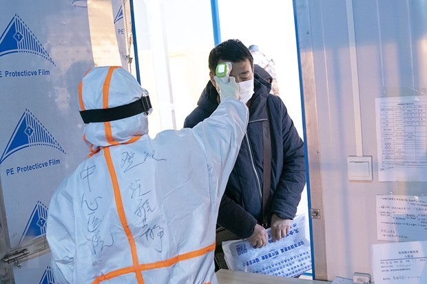 Nhân viên y tế kiểm tra thân nhiệt cho bệnh nhân nhiễm Covid-19 tại một bệnh viện dã chiến ở Vũ Hán, Trung Quốc ngày 5/2/2020. (Nguồn: THX/TTXVN).