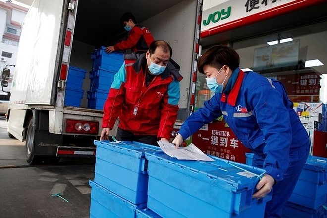 Công nhân trạm xăng của Sinopec tại Bắc Kinh bốc dỡ các thùng rau củ quả ngày 28/2. Đây là dịch vụ mới của Sinopec, gọi là đặt mua thực phẩm "không chạm" mùa dịch. Ảnh: Reuters.