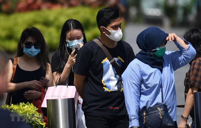 Người dân đeo khẩu trang phòng dịch COVID-2 tại Singapore. (Ảnh: AFP/TTXVN).