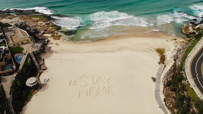 Lời kêu gọi ở nhà để tuân thủ quy định giãn cách xã hội được viết trên một bãi biển ở Sydney. Nguồn Getty.