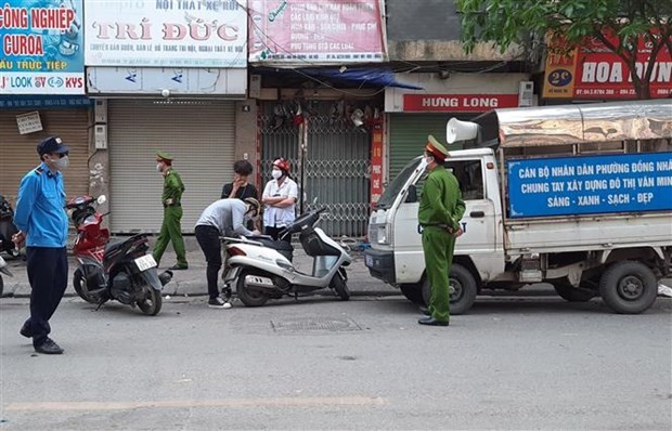 Tổ công tác phường Đồng Nhân (quận Hai Bà Trưng, Hà Nội) xử phạt các trường hợp vi phạm không đeo khẩu trang ra đường. (Ảnh: Doãn Tấn/TTXVN).