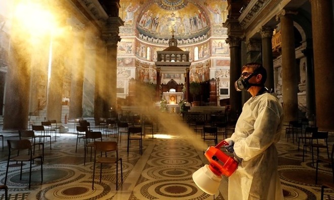 Người đàn ông khử trùng bên trong nhà thờ Santa Maria in Trastevere Basilica ở Rome, Italy, ngày 11/5. Ảnh: Reuters.