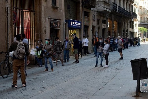 Người dân xếp hàng khi các tình nguyện viên phân phát thực phẩm tại nhà thờ Santa Anna ở Barcelona vào ngày 15/5/2020. (Nguồn: AFP).