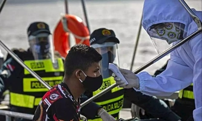 Nhân viên y tế chính phủ Brazil phối hợp cùng cảnh sát kiểm tra thân nhiệt cho một khách đi tàu ở bang Para hôm 27/5. Ảnh: AFP.
