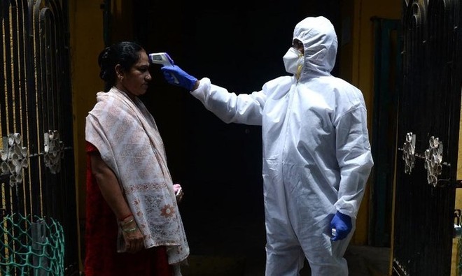 Một bác sĩ kiểm tra thân nhiệt cho người dân tại nơi cư trú ở thành phố Chennai, Ấn Độ, hôm 29/6. Ảnh: AFP.