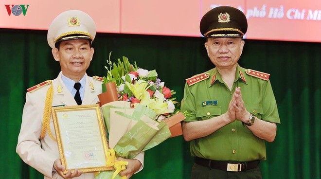 Đại tướng Tô Lâm thừa uỷ quyền của Chủ tịch nước trao quyết định và tặng hoa chúc mừng Thiếu tướng Đinh Thanh Nhàn.