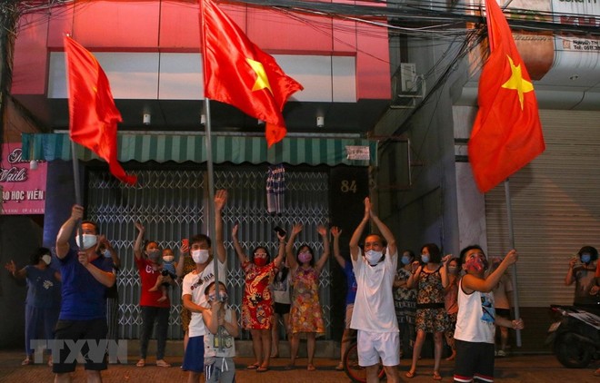 Người dân ở trên tuyến đường Nguyễn Thị Minh Khai vui mừng sau khi hoàn thành cách ly 14 ngày trong khu vực phong tỏa. (Ảnh: Trần Lê Lâm/TTXVN).