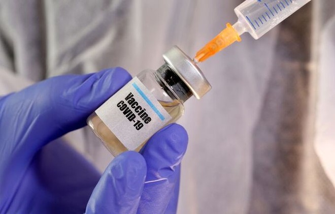 Một phụ nữ cầm lọ dán nhãn vaccine Covid-19 và ống tiêm trong hình ảnh minh hoạ được chụp hôm 10/4. Ảnh: Reuters.