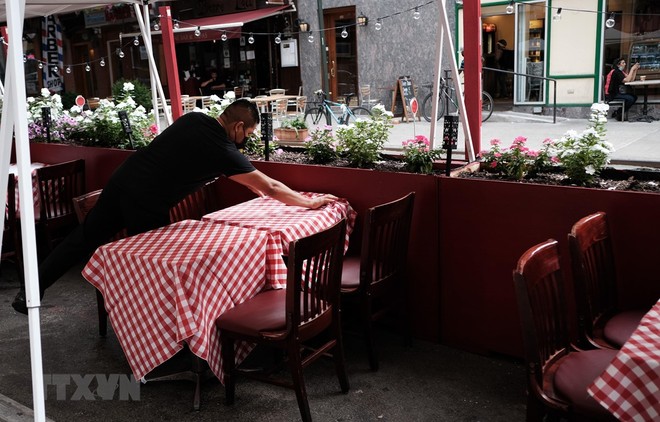 Nhân viên sửa soạn lại bàn ghế tại một nhà hàng ở New York, Mỹ. (Ảnh: AFP/TTXVN).
