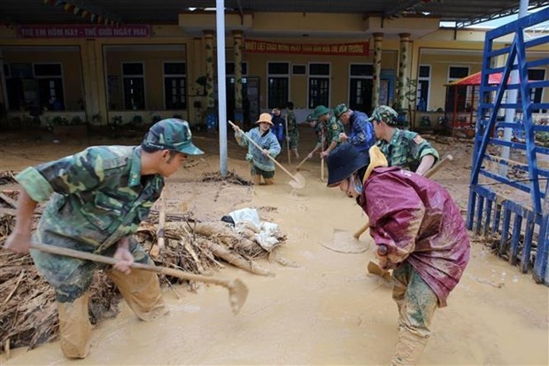 Bộ đội giúp địa phương xã Hướng Việt thu dọn bùn đất tại trường học. (Ảnh: Hồ Cầu/TTXVN).