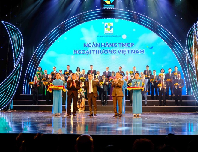 Đại diện Vietcombank, ông Lê Hoàng Tùng – Kế toán trưởng nhận biểu trưng Thương hiệu quốc gia cùng hoa chúc mừng từ Bộ trưởng Bộ Công thương Trần Tuấn Anh và đại diện Hội đồng Thương hiệu Quốc gia.