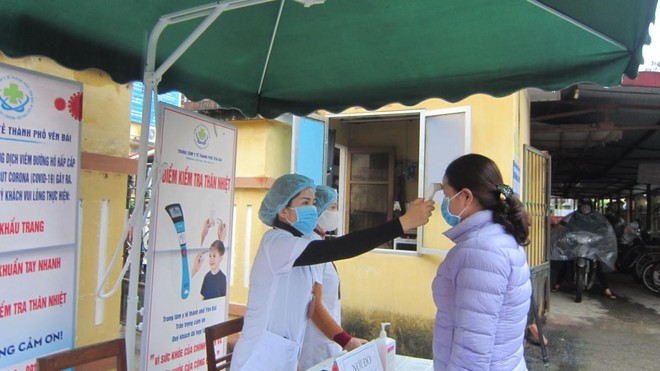 Cán bộ Trung tâm Y tế thành phố Yên Bái kiểm tra thân nhiệt cho bệnh nhân đến khám tại đơn vị (Ảnh: KT).