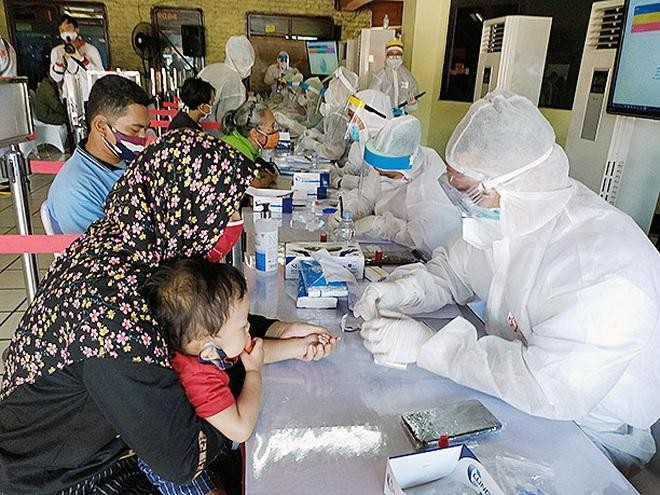 Một người mẹ cho con nhỏ xét nghiệm Covid-19 ở Jakarta, Indonesia (Ảnh: Jakarta Post).