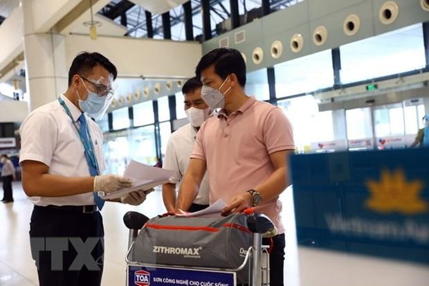 Nhân viên của Vietnam Airlines kiểm tra giấy tờ của hành khách trước khi vào làm thủ tục. (Ảnh: Huy Hùng/TTXVN).