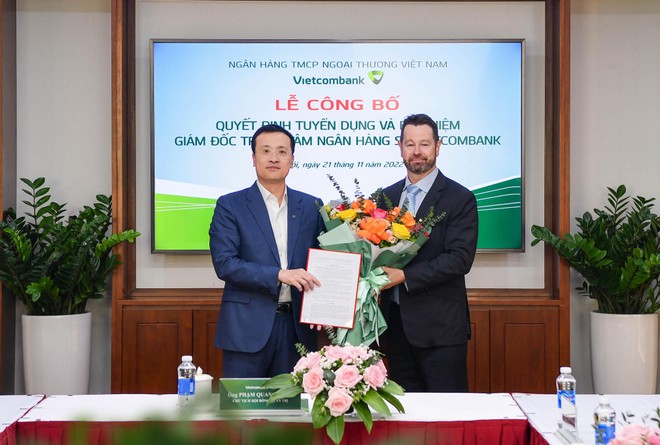 Ông Phạm Quang Dũng, Chủ tịch HĐQT Vietcombank (bên trái) trao quyết định và tặng hoa chúc mừng tân Giám đốc Trung tâm ngân hàng số Vietcombank.