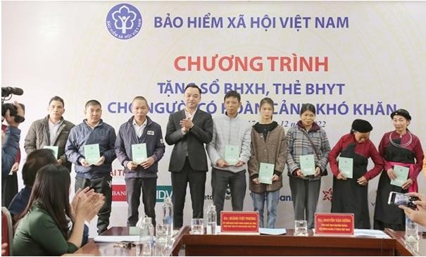 Phó Chủ tịch chuyên trách HĐQL BHXH Nguyễn Văn Cường trao tặng sổ BHXH, thẻ BHYT tới người dân.
