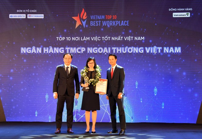 Ông Trương Minh Tiến - Phó tổng giám đốc Viet Research (bên phải) và ông Đặng Tuấn Khánh - Ủy viên Ban Biên tập Báo Đầu tư (bên trái) trao biểu trưng và chứng nhận Top 10 Nơi làm việc tốt nhất Việt Nam cho bà Tô Thị Phương Dung - Trưởng phòng Chính sách và kế hoạch nhân sự Vietcombank.