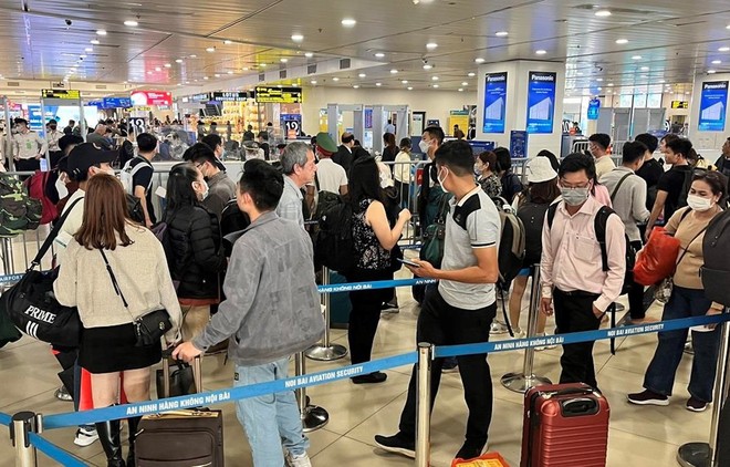 Hành khách xếp hàng dài chờ vào khu vực kiểm tra giấy tờ tùy thân và soi chiếu an ninh tại sân bay Nội Bài. (Ảnh: CTV/Vietnam+).