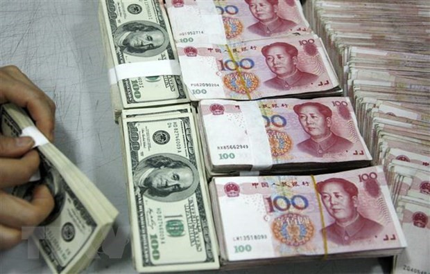 Nhân viên kiểm đồng USD (trái) và đồng nhân dân tệ tại một ngân hàng ở tỉnh An Huy, Trung Quốc. (Ảnh: AFP/TTXVN).