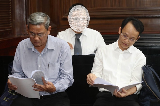 Bị cáo Lê Văn Thanh (bên trái) và Nguyễn Thanh Chương (bên phải) đang xem lại tại liệu trước khi xét xử. (ảnh Lê Toàn)