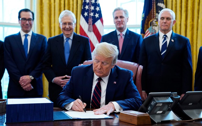 Tổng thống Mỹ Donald Trump ký gói cứu trợ Covid-19 tại Nhà Trắng ngày 27/3. Phía sau từ trái qua bao gồm Bộ trưởng Tài chính Steven Mnuchin, Lãnh đạo đa số tại Thượng viện Mitch McConnell,  Lãnh đạo thiểu số tại Hạ viện Kevin McCarthy và Phó Tổng thống Mike Pence. Ảnh: AP.