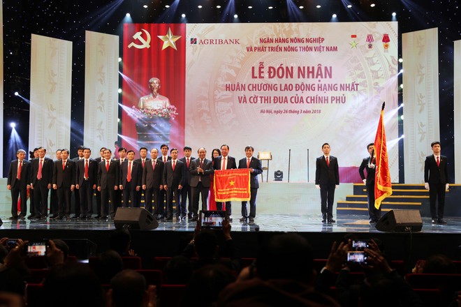 Thủ tướng Chính phủ Nguyễn Xuân Phúc gắn Huân chương Lao động hạng Nhất lên Lá cờ truyền thống của Agribank.