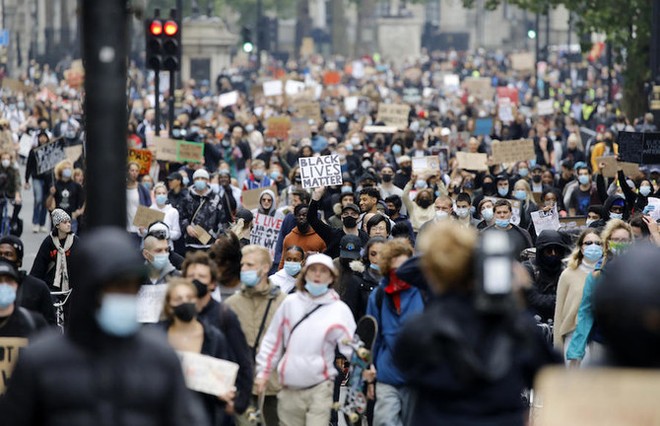 Các nhà hoạt động cầm biểu ngữ, đeo khẩu trang phòng dịch Covid-19 khi tham gia cuộc tuần hành theo phong trào hoạt động quốc tế "Black Lives Matter" (Người da đen đáng được sống) đến Quảng trường Trafalgar, London vào ngày 12/6/2020. Ảnh tư liệu: AFP
