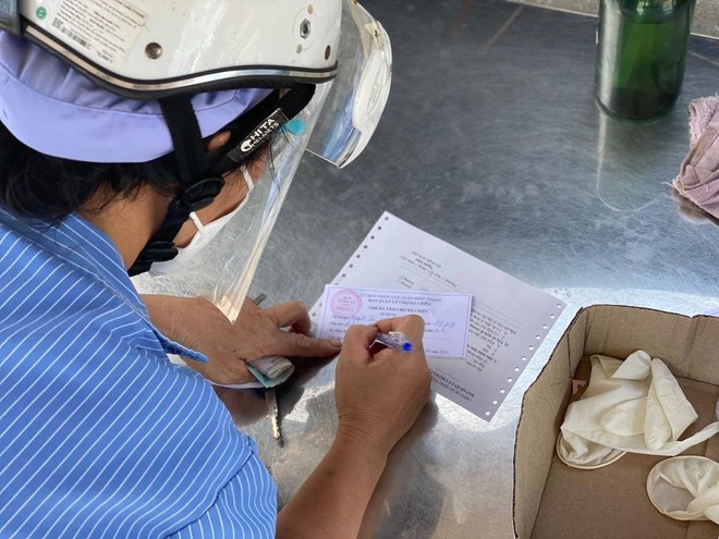 Người dân tại TP.HCM điền thông tin vào thẻ ra vào chợ Bà Chiểu, quận Bình Thạnh (Ảnh: Q.T).
