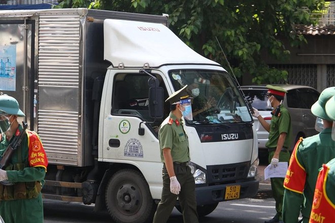 Lực lượng chức năng tại chốt kiểm soát kiểm tra giấy tờ lưu thông của tài xế vận chuyển lương thực, thực phẩm. (ảnh: Lê Toàn)