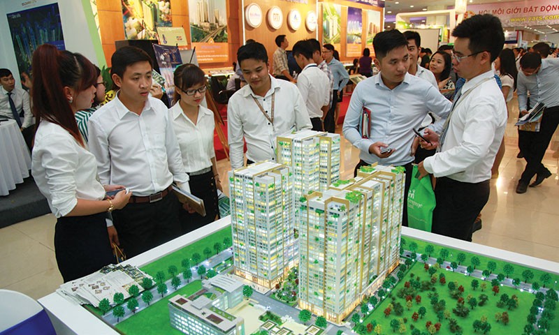 Nhân viên môi giới bất động sản giới thiệu dự án với 
khách hàng tại một hội chợ bất động sản diễn ra tại Hà Nội. Ảnh: Dũng Minh